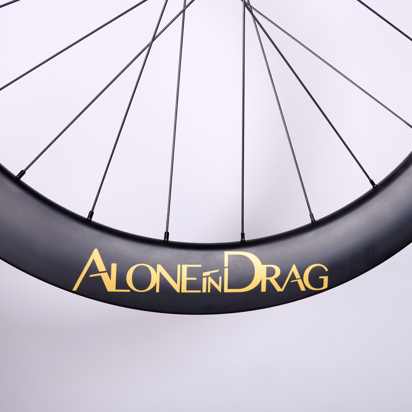Close-up of the SaBRe VI.V rim with the gold Alone in Drag logo, studio shot
